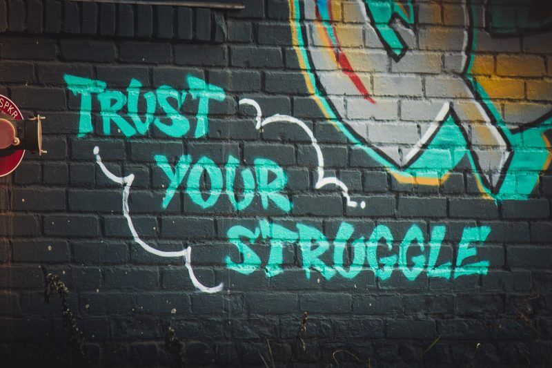Graffiti on a wall saying trust your struggle when fulfilling your dreams